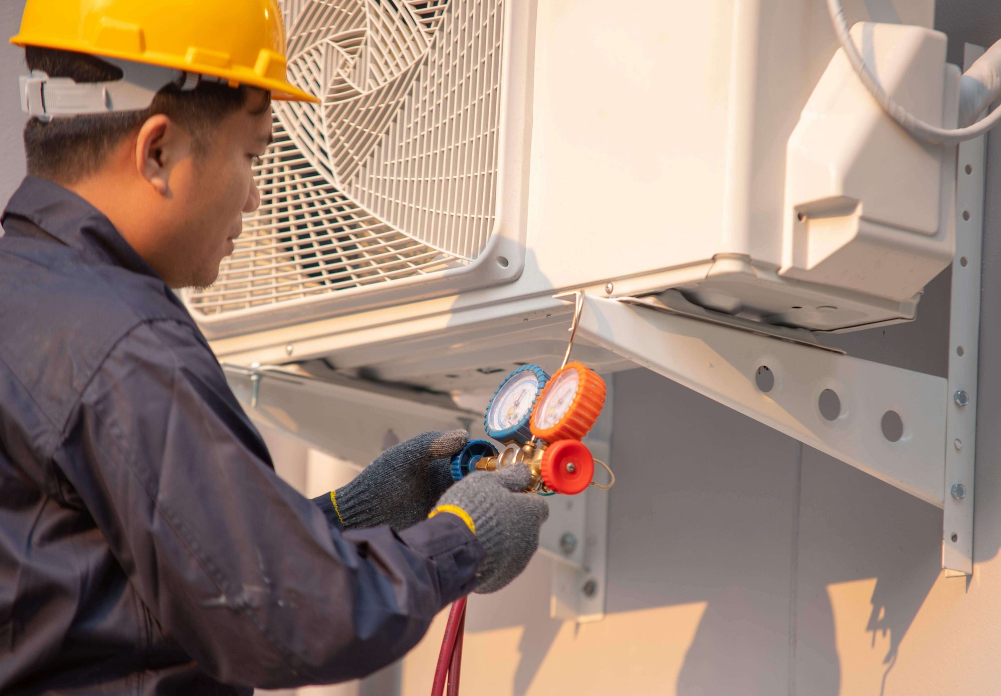 Technician checking refrigerant gauges on an outdoor air conditioning unit