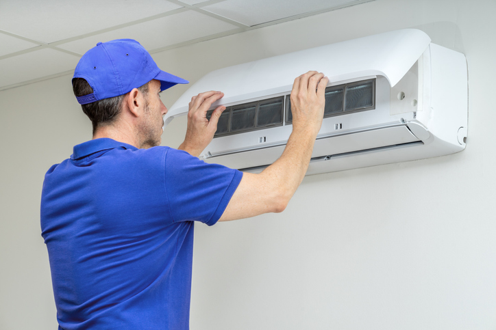 Technician opening a wall-mounted air conditioner to clean its filters