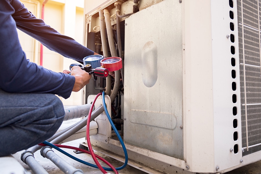 Technician connecting pressure gauges to an air conditioner